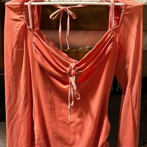 A dress in a vibrante orange-pink color that is perfect for a sunny day.
